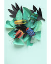 Colorful paper beetles on green leaves against a light blue background