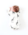 Baby wrapped in a white blanket with black giraffe patterns on a white background