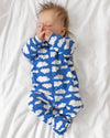 Baby wearing a blue onesie with white cloud pattern on a white background