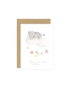 A baby greeting card with an illustration of an elephant, moon, rainbow, owl, and stars on a cloud mobile. The card has a beige background and a blank inside for a personal message.