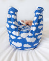 Baby in a blue and white cloud-patterned baby carrier on a white background