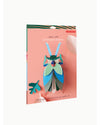 Packaged wall art of an emerald beetle on a pink background