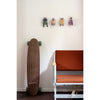 Skateboard leaning against a wall with decorative beetle figures above, next to a chair.