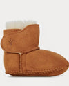 Brown baby bootie with white fur lining on a light gray background