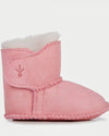 Pink baby booties with white fur lining on a light gray background