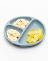 Light blue divided plate with banana and apple pieces on a white background