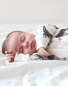 Newborn baby sleeping in a crib with a black and white patterned blanket