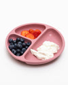 Pink divided plate with strawberries, blueberries, and yogurt on a white background