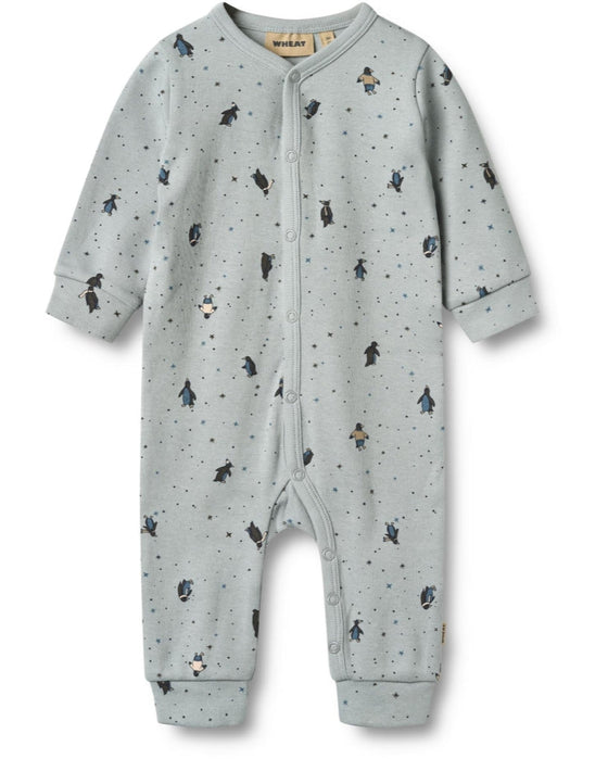 Long-sleeved jumpsuit for babies with a wheat signature print and penguin patterns, featuring press buttons down the front and along the inseam.