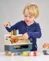 Two children playing with a toy workshop set on a gray background
