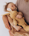 Baby holding a brown teddy bear with a blurred background