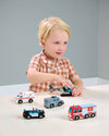 Child playing with toy cars on a table against a gray background