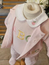 A baby outfit displayed on a mannequin torso, featuring a light pink knit romper with embroidered letters 'A', 'B', and 'C' in gold, green, and pink, a matching light pink jacket draped over the shoulders, and a cream-colored collar with a small embroidered pink apple.
