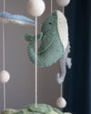 Decorative mobile with green whale and white balls against a dark background