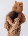 Child hugging a large brown teddy bear against a white background