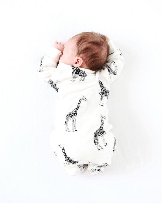 Baby wrapped in a white blanket with black giraffe patterns on a white background