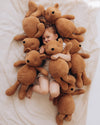 Child surrounded by teddy bears on a soft surface