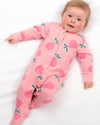 Baby wearing a pink strawberry print onesie on a white blanket