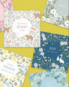 Collection of baby-themed cards with floral and nature designs on a yellow background.