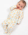 Baby wearing a white onesie with yellow giraffe patterns on a white background