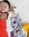 Baby sleeping with a striped toy on a textured surface
