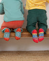 Two children sitting on a wooden step wearing colorful socks with patterns.
