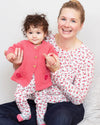 Woman holding a baby wearing a pink cardigan and matching outfit against a white background
