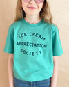 Child wearing a teal t-shirt with 'Ice Cream Appreciation Society' text on a beige background
