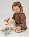 Child playing with a toy kitchen set on a plain background