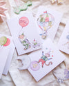 Set of children's cards with illustrations of a clown, balloon, and other decorative elements on a soft fabric background.