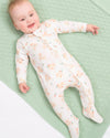 Baby lying on a green textured blanket wearing a patterned onesie.