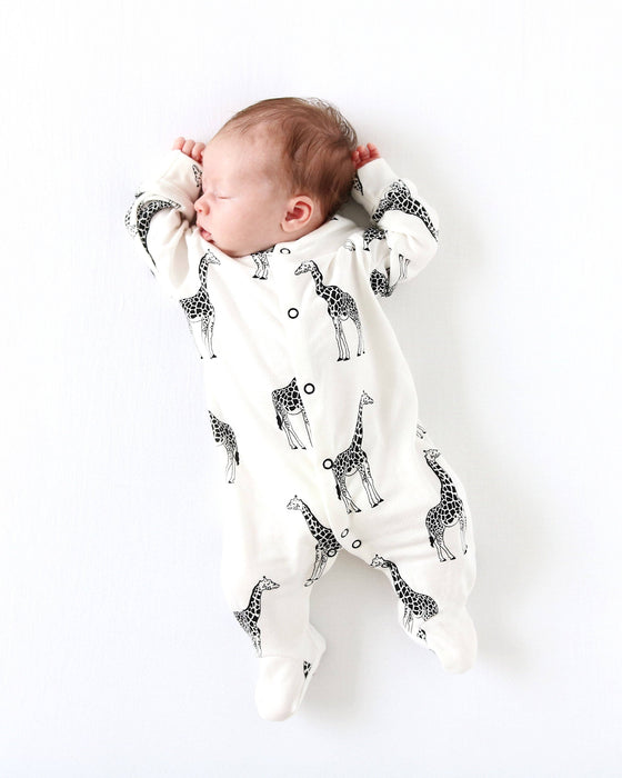 Newborn baby wrapped in a white swaddle with black giraffe pattern on a white background