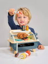Child playing with a toy kitchen set on a plain background