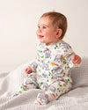 Baby wearing a onesie with animal prints sitting on a white blanket.