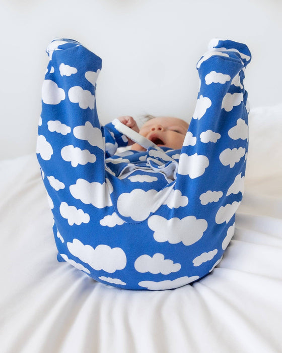 Baby in a blue and white cloud-patterned baby carrier on a white background