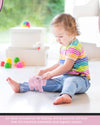 Child playing with a toy in a bright room with toys scattered around