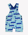 Blue children's overalls with whale pattern on a white background