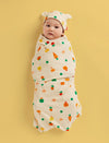 Baby swaddled in a colorful blanket with a yellow background