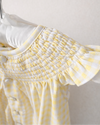 Yellow and white polka dot dress on a hanger against a white background