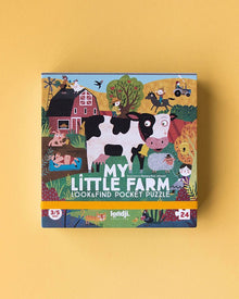  A colorful children's puzzle box with an illustration of a farm and its animals, including a cow, sheep, pig, and chicken, on a yellow background.