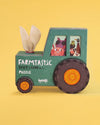 Toy puzzle box shaped like a green tractor with animal illustrations on a yellow background