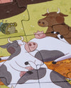 Children's puzzle with cartoon animals including cows and pigs on a grassy field.