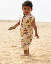 Child in a cherry-patterned outfit standing on sand