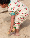 Child playing in the sand wearing a floral outfit