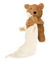 Brown teddy bear holding a cream-colored blanket with 'wooly organic' branding on a white background.