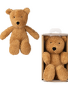 Brown teddy bear next to a teddy bear in a cardboard packaging on a white background