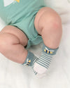Baby wearing green shorts and striped socks on a white background
