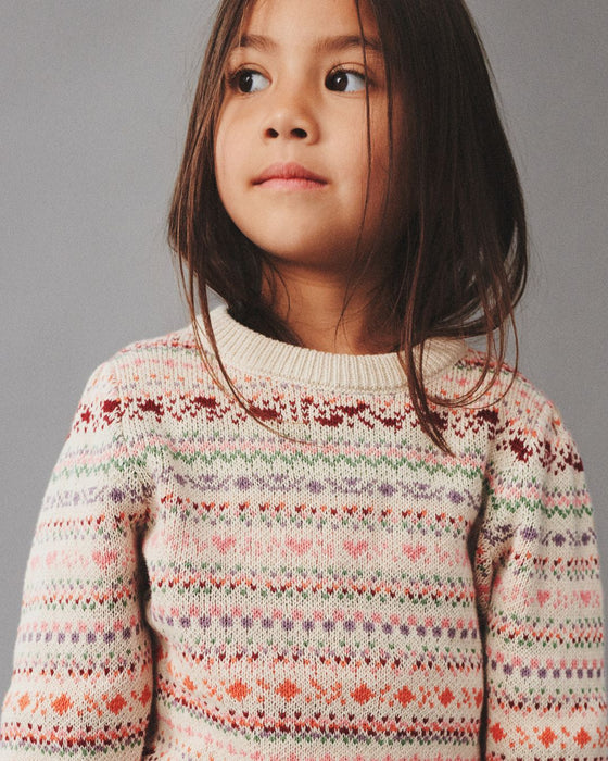 Child wearing a patterned sweater against a gray background