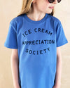 Child wearing a blue t-shirt with 'Ice Cream Appreciation Society' text on a beige background