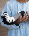 Child holding a soft toy with zebra pattern, wearing a light blue dress.